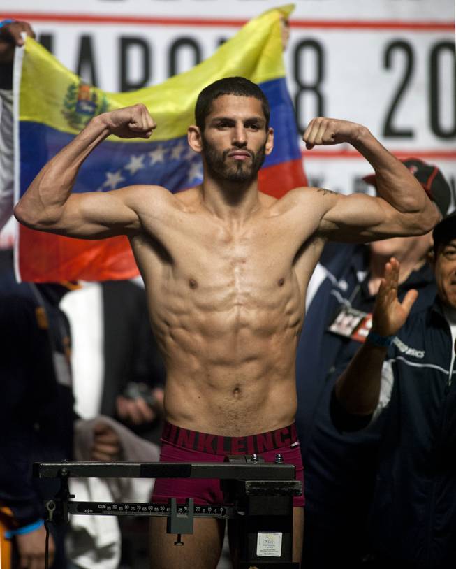 Lightweight Jorge Linares of Venezuela flexes for the crowd while on the scale during his weigh-in at the MGM Grand Arena on Friday, March 07, 2014.